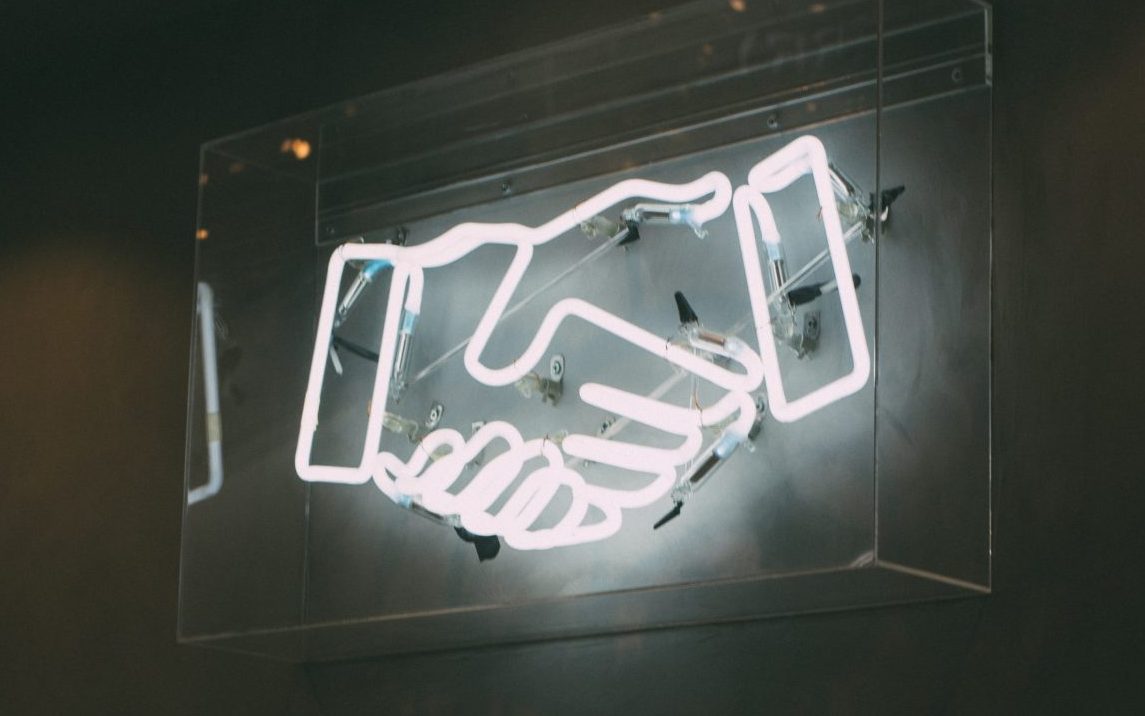 Neon sign of hands shaking