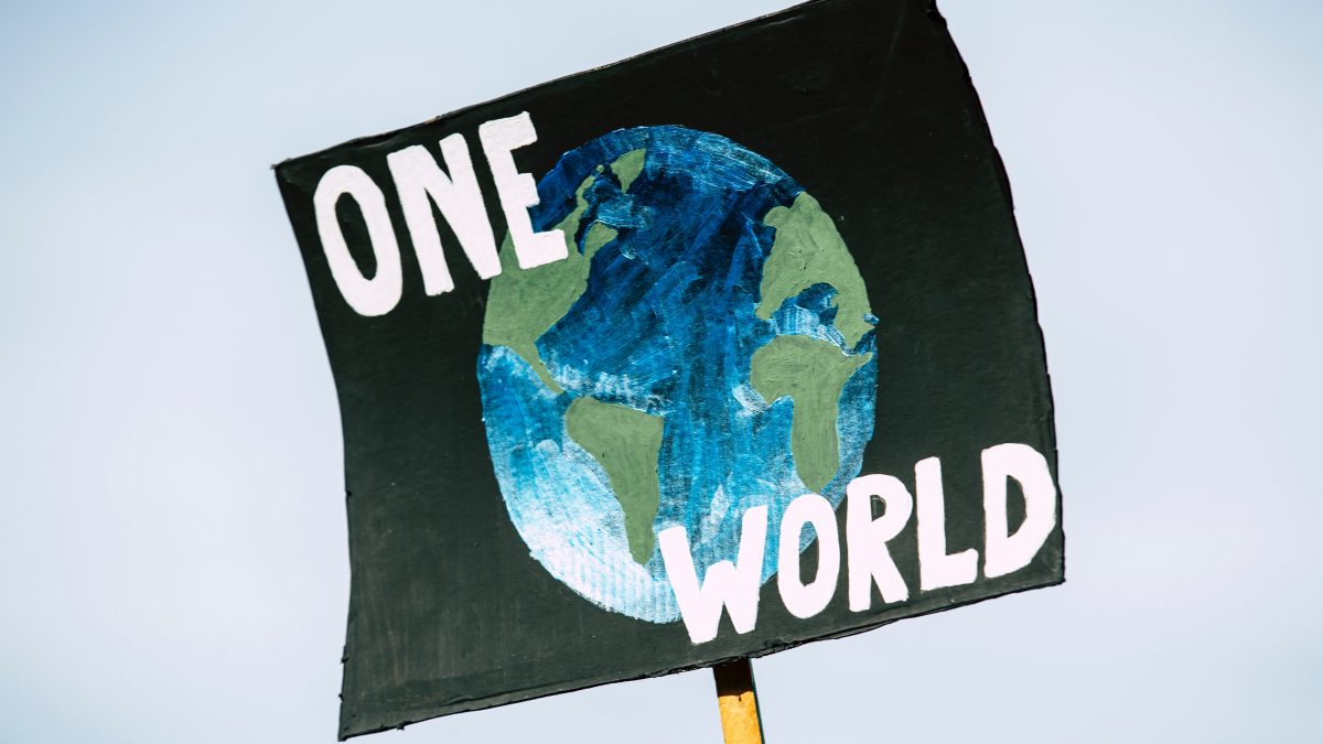 poster held in the sky with an image of the world and the words ONE WORLD written